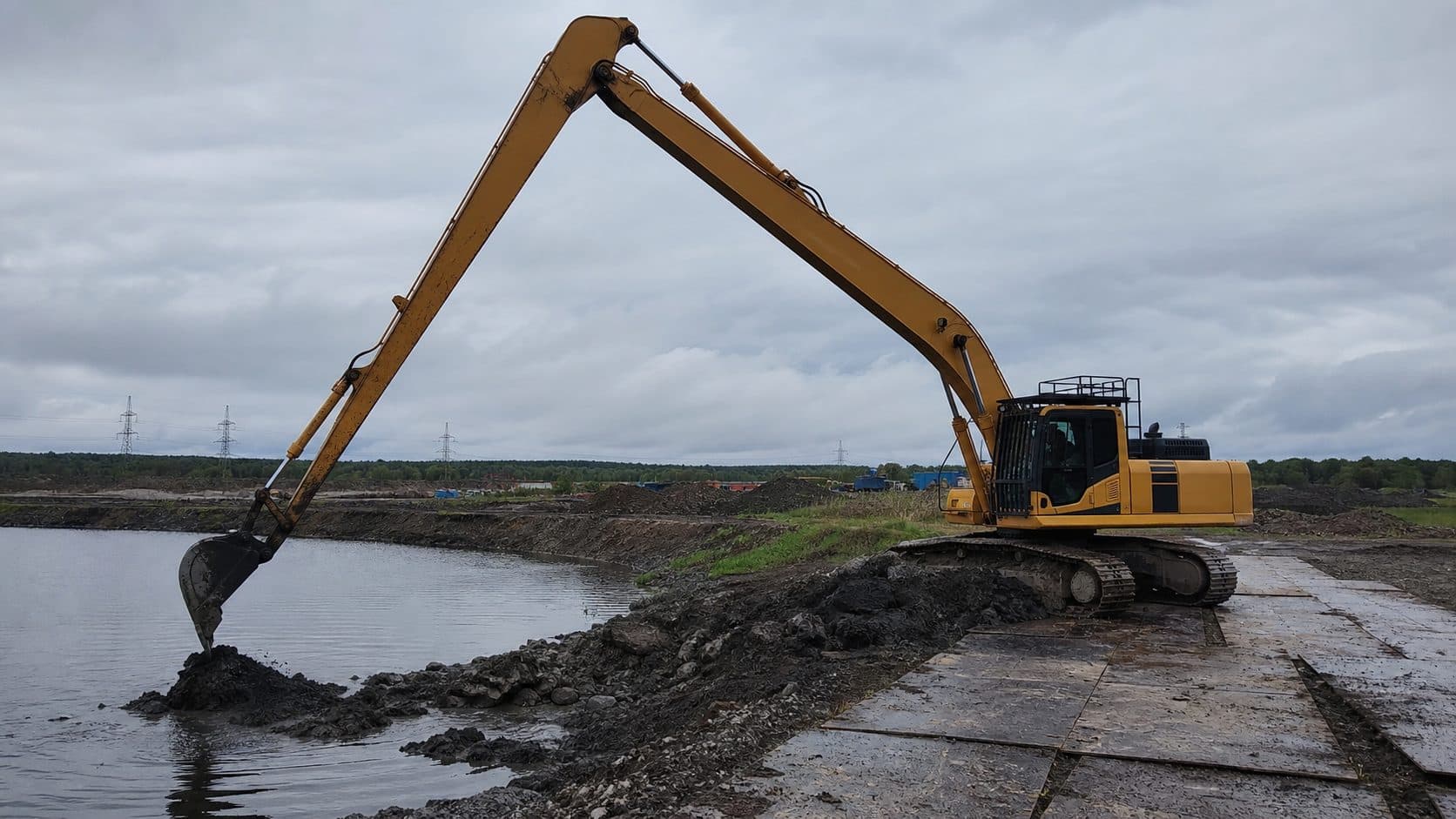 Гусеничный экскаватор Long Reach работает у кромки водоема